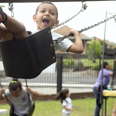A Projects Abroad volunteer pushes a young boy on a swing during her Childcare volunteer work in Costa Rica Children play on the swings under the supervision of a volunteer working with children in Costa Rica